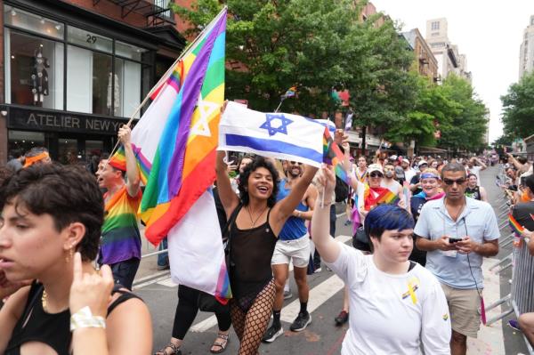 Pride parade crowd, person in bathing suit and fishnets holding an israel flag prominently featured.