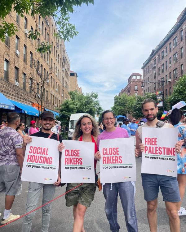 Four marchers at the Queens Pride parade holding signs advocating for Free Palestine and Queer Liberation, and posters promoting the closing of Rikers Island and the funding of libraries