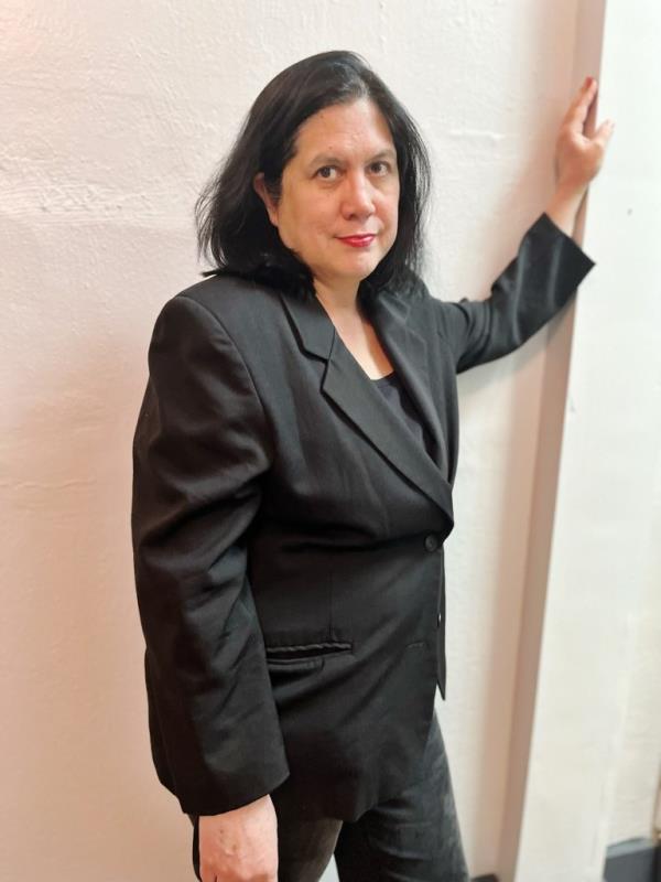 Lawyer Paula Collins in a suit leaning against a wall, representing smoke shop owners