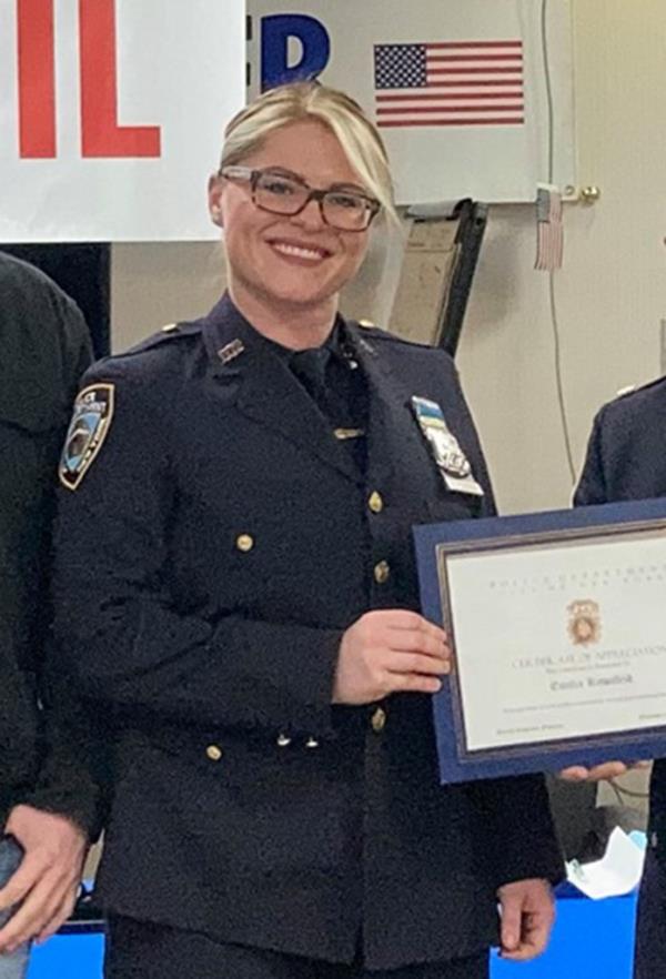 The cop smiles as she holds a certificate.