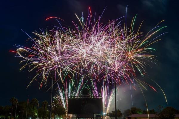 Fireworks display by the Jackso<em></em>nville Jumbo Shrimp for 2023 Independence Day celebration, fireworks seen shooting above homes and street signs in bright rainbow colors