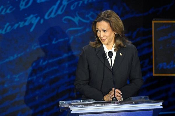 US Vice President Kamala Harris at a podium, listening to former President Do<em></em>nald Trump during a presidential debate at the Natio<em></em>nal Co<em></em>nstitution Center